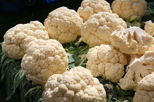 A vibrant display of fresh cauliflower heads at an outdoor market, showcasing natural textures and colors.