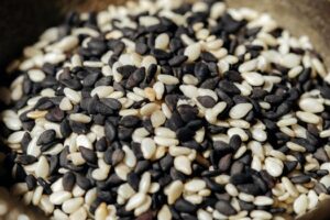 A high-resolution close-up photo of mixed black and white sesame seeds, showcasing texture and detail.