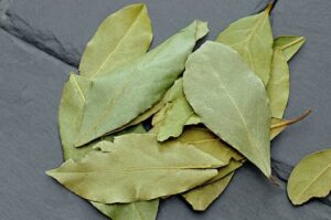A close-up photo of dried bay leaves on a textured slate surface, ideal for spice and culinary themes.